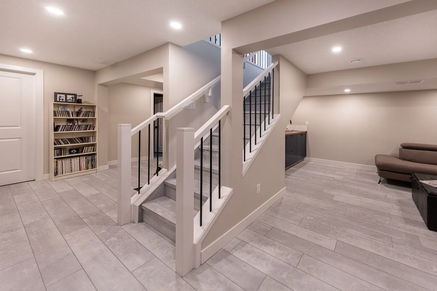 Finished basement with an open stair railing, built-in shelving and plank flooring in Lilburn, GA
