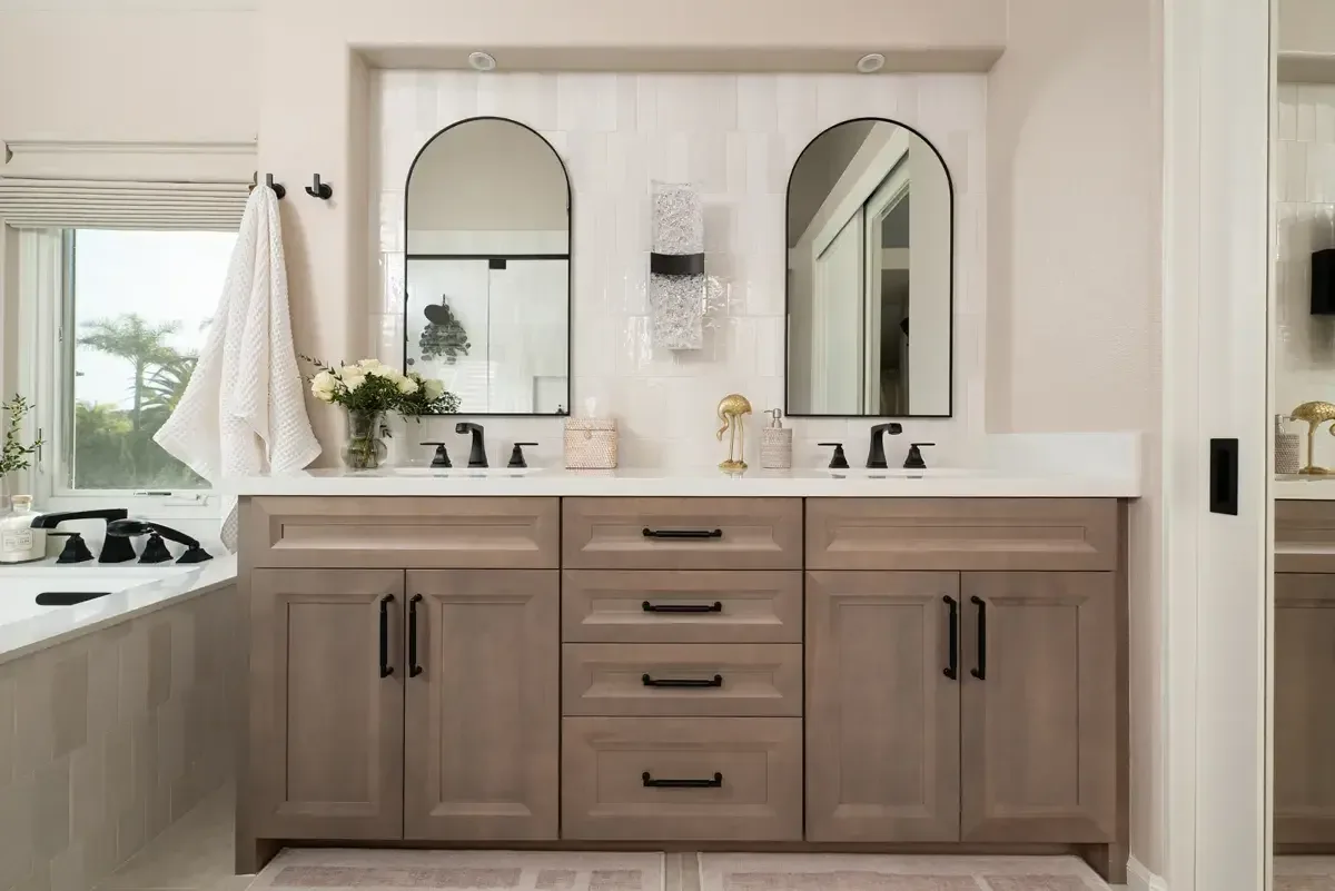 Double wood vanity with arched mirrors and a soaking tub in a Gwinnett County primary bathroom