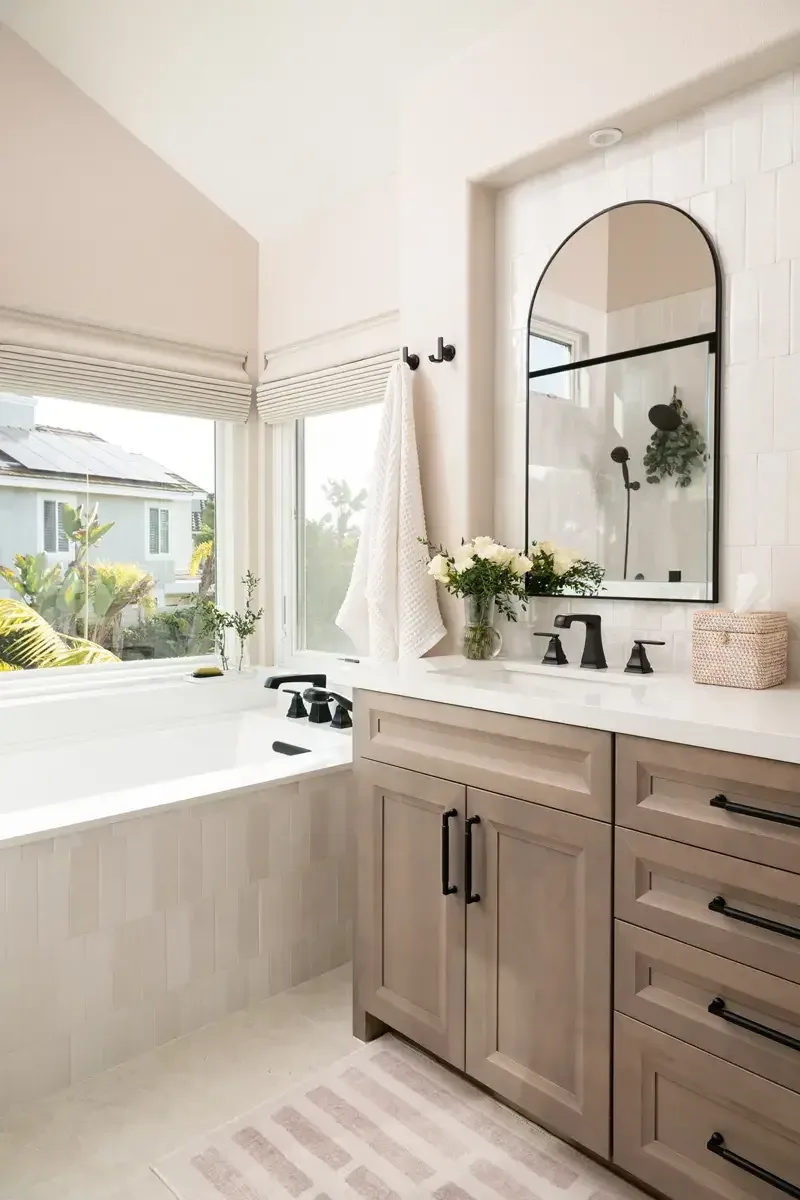 Wood vanity and alcove soaking tub beneath a window in a finished Dacula, GA bathroom