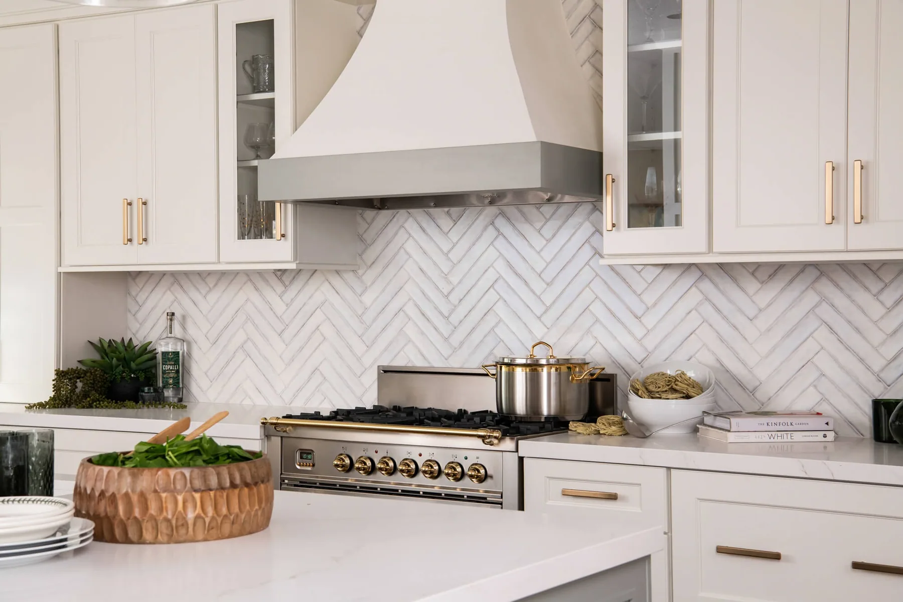 Custom range wall with a plaster hood and herringbone marble backsplash in a Duluth, GA kitchen