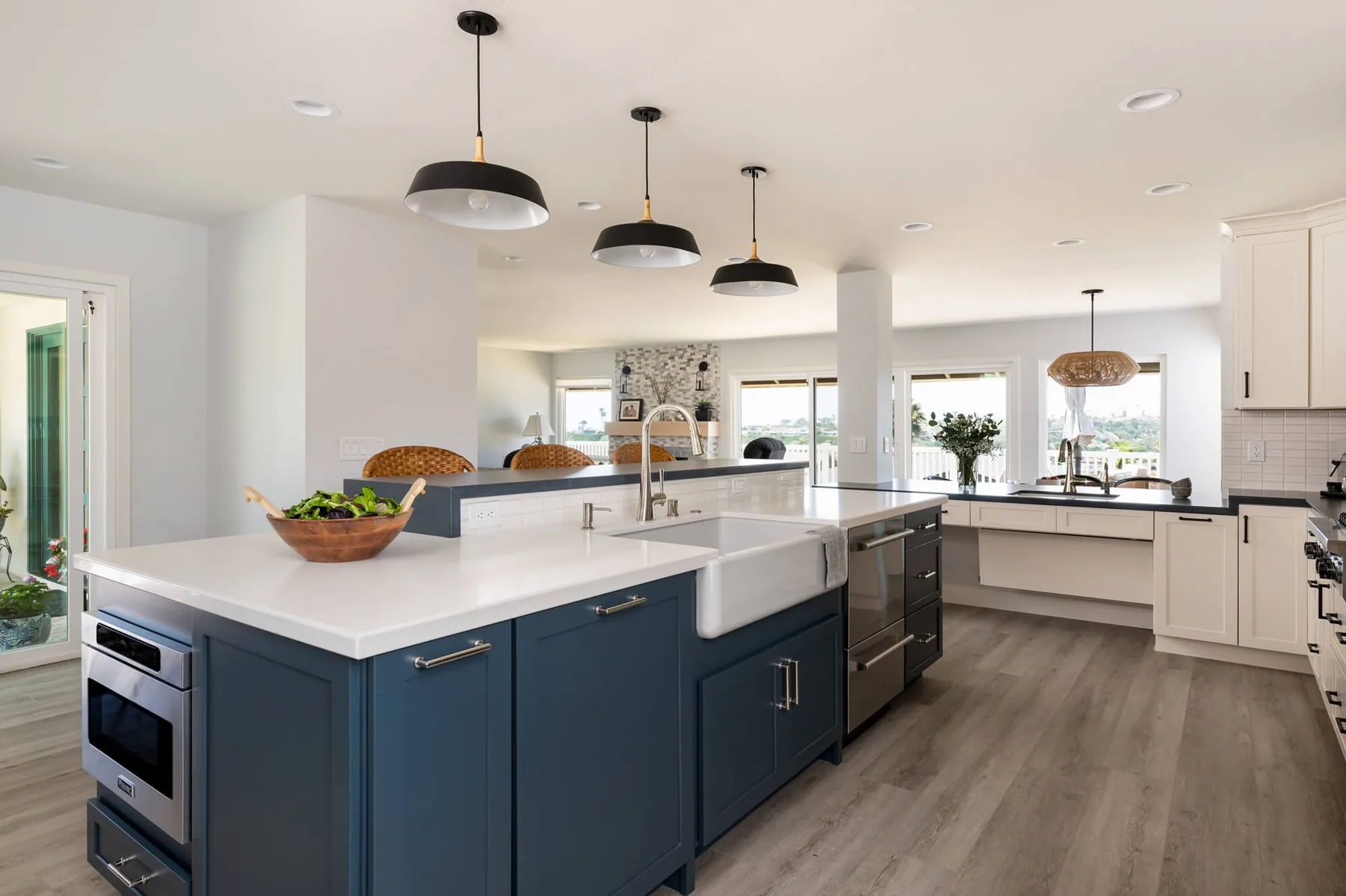 Open-concept kitchen renovation with a navy island and farmhouse sink opening to the living room